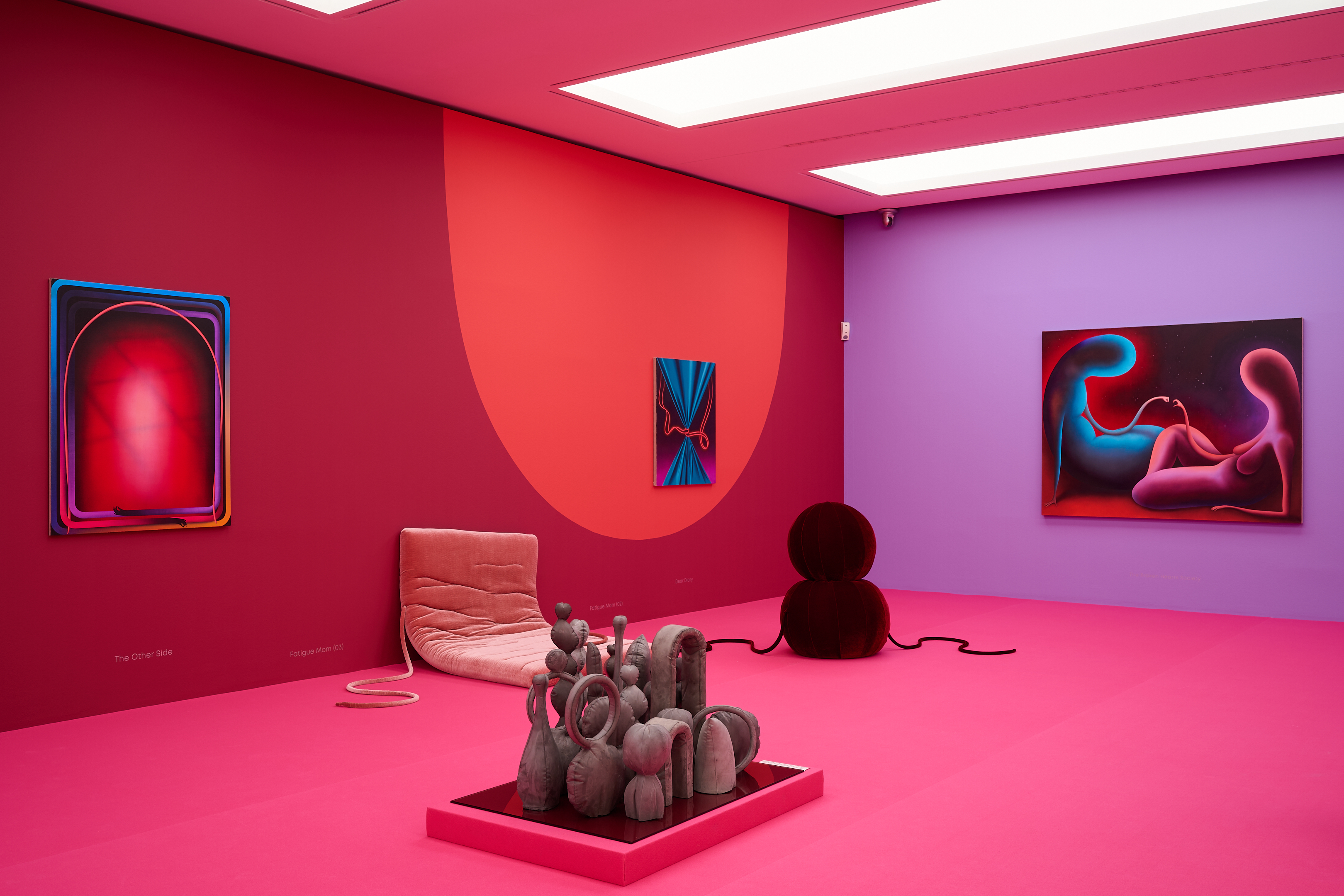KI generiert: Das Bild zeigt einen farbenfrohen Ausstellungsraum mit moderner Kunst, unter anderem Skulpturen und Gemälde. Die dominierenden Farben sind kräftige Pink-, Rot- und Lilatöne, die eine lebendige Atmosphäre schaffen.