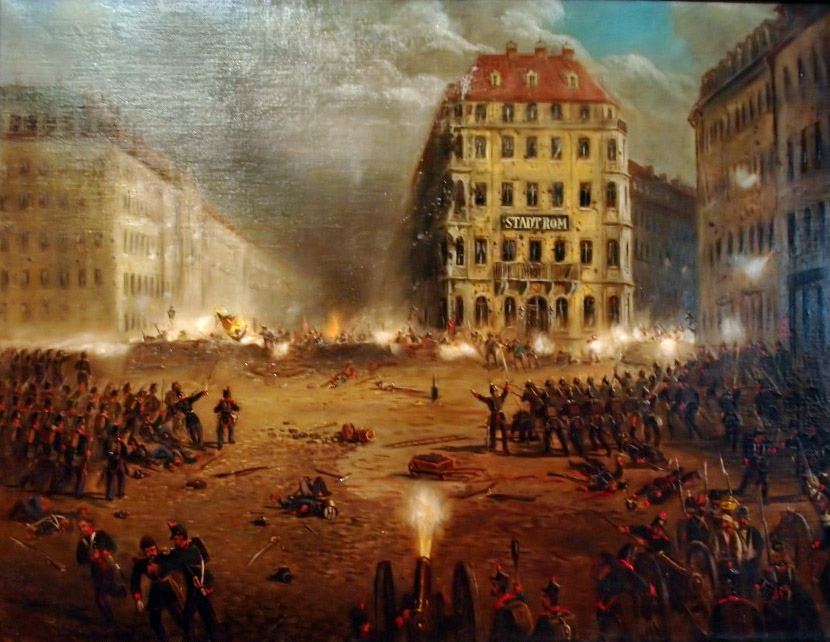 KI generiert: Das Bild zeigt eine historische Straßenschlacht mit Soldaten, Artillerie und einem brennenden Gebäude im Hintergrund. Die Szene vermittelt Chaos und Intensität eines Kampfes in einer urbanen Umgebung.