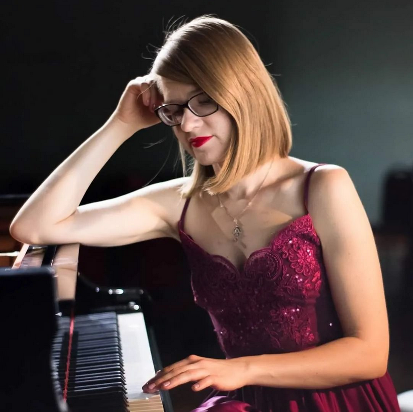 KI generiert: Das Bild zeigt eine Frau in einem eleganten, burgunderroten Kleid, die nachdenklich neben einem Klavier sitzt. Sie stützt ihren Kopf mit der Hand und trägt eine Brille.