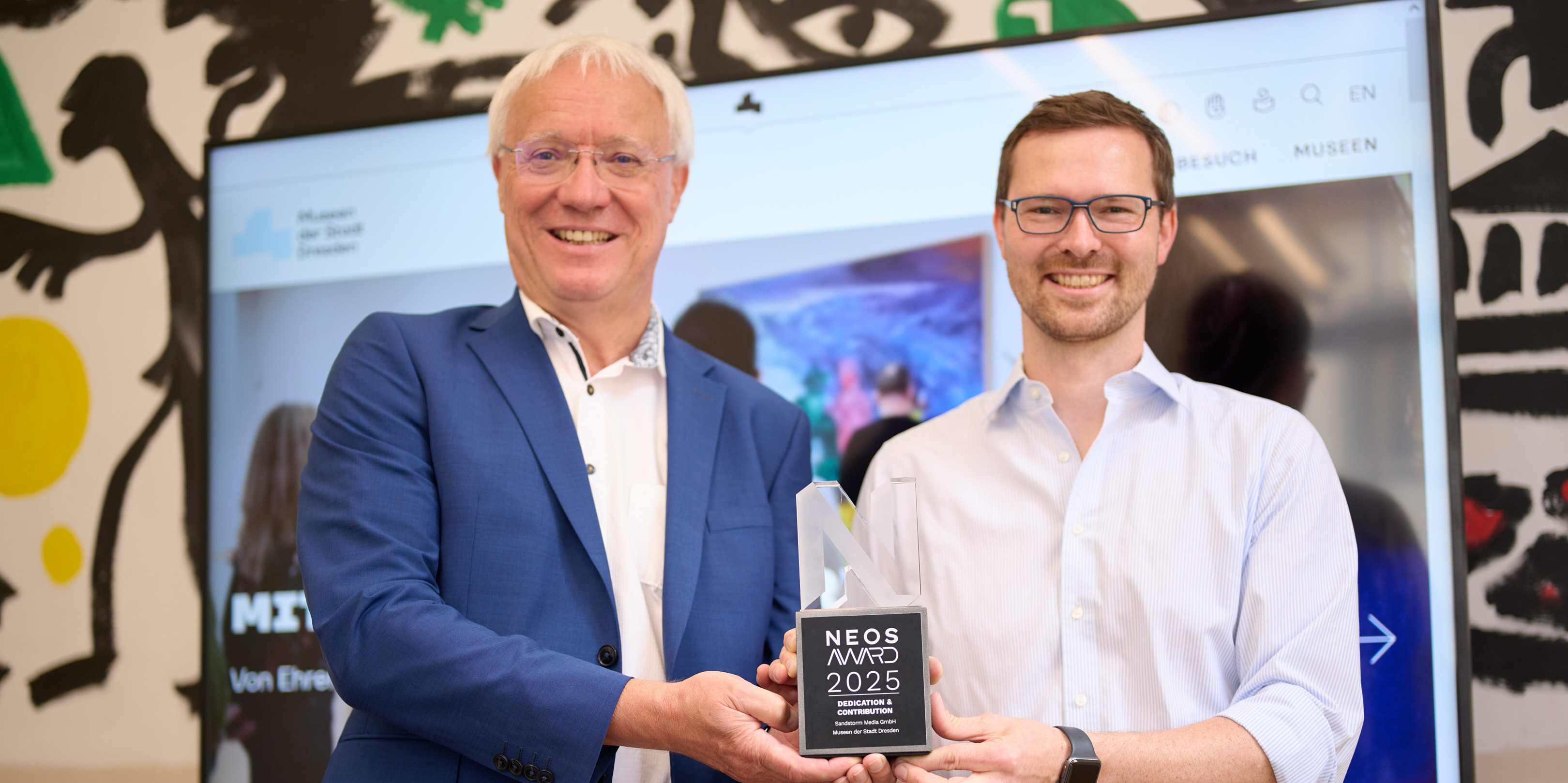 KI generiert: Zwei Männer stehen nebeneinander und präsentieren gemeinsam eine Trophäe mit der Aufschrift "Neos Award 2025". Im Hintergrund ist ein Bildschirm mit einem nicht lesbaren Bild oder einer Präsentation zu sehen.