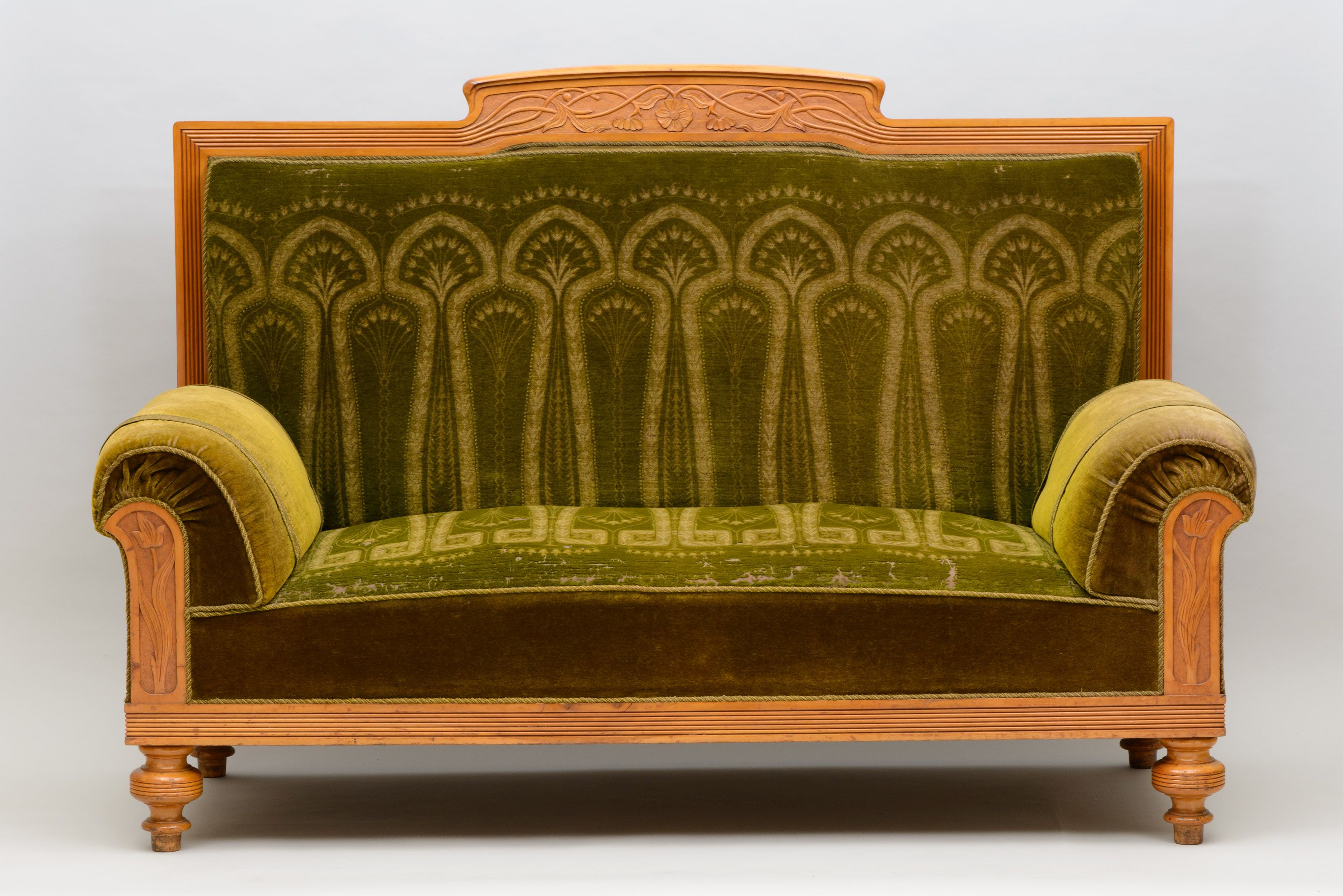 AI generated: The image shows an antique sofa with green fabric upholstery and ornate wood carvings on the backrest and armrests. The design of the sofa is classic and decorative.
